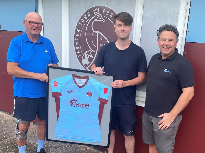 Kevin Sturmey, Taunton Town FC Chairmen presents a framed shirt to a service user from Cygnet Hospital Taunton and active life lead Stu Hooper