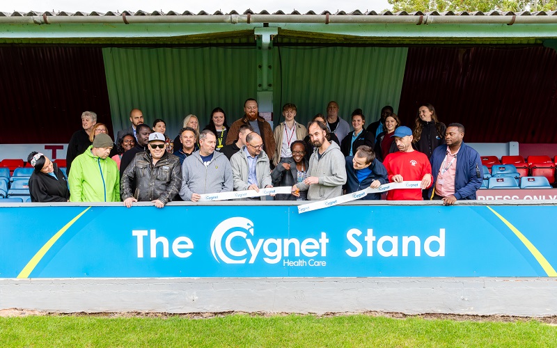 Service users and staff from Cygnet Hospital Taunton join Taunton Town FC staff to cut the ribbon to open the Cygnet Health Care Stand