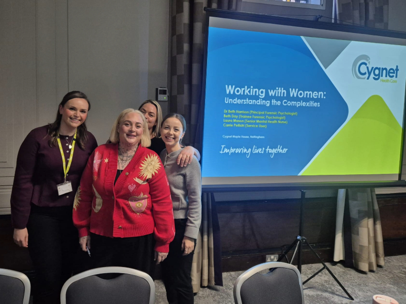 Colleagues and a service user from Cygnet Maple House standing beside a presentation screen titled ‘Working with Women: Understanding the Complexities’ at the Female Collaboration Day event.