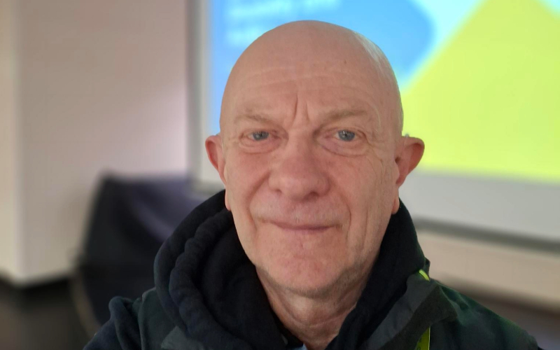 A selfie of Keith in front of a presentation screen displaying a “Learning Disability and Autism” training slide, reflecting their role delivering LD and autism training as part of their neurodiversity journey.