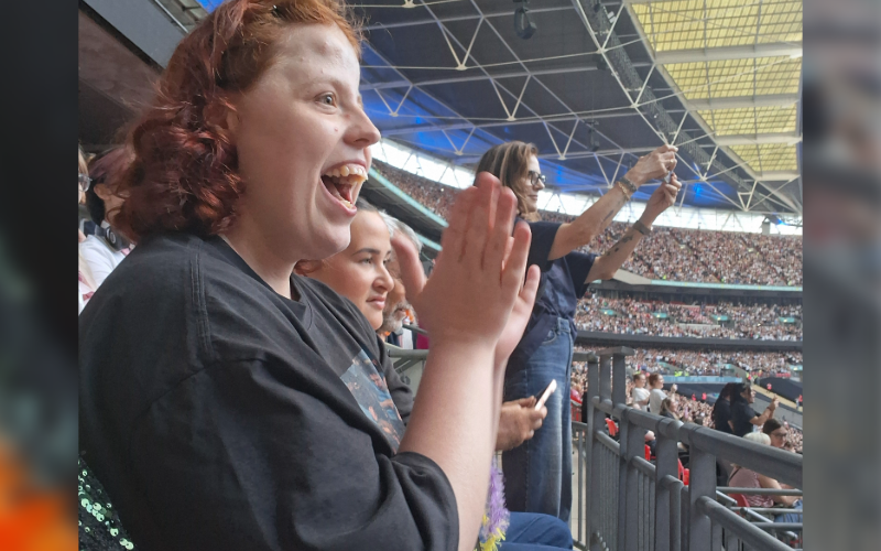 A supported individual clapping in the crowd at the Harry Styles concert at Wembley