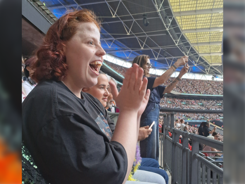 A supported individual clapping in the crowd at the Harry Styles concert at Wembley