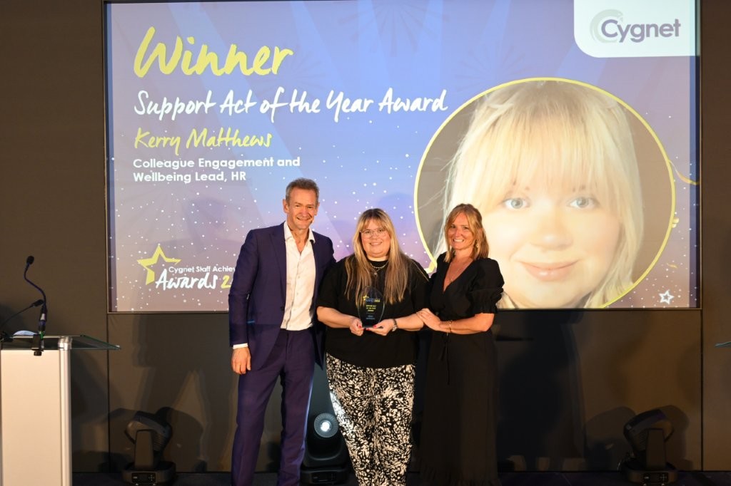 The winner of the Support Act of the Year Award on stage with Head of HR Jenny Gibson and celebrity host Alexander Armstrong