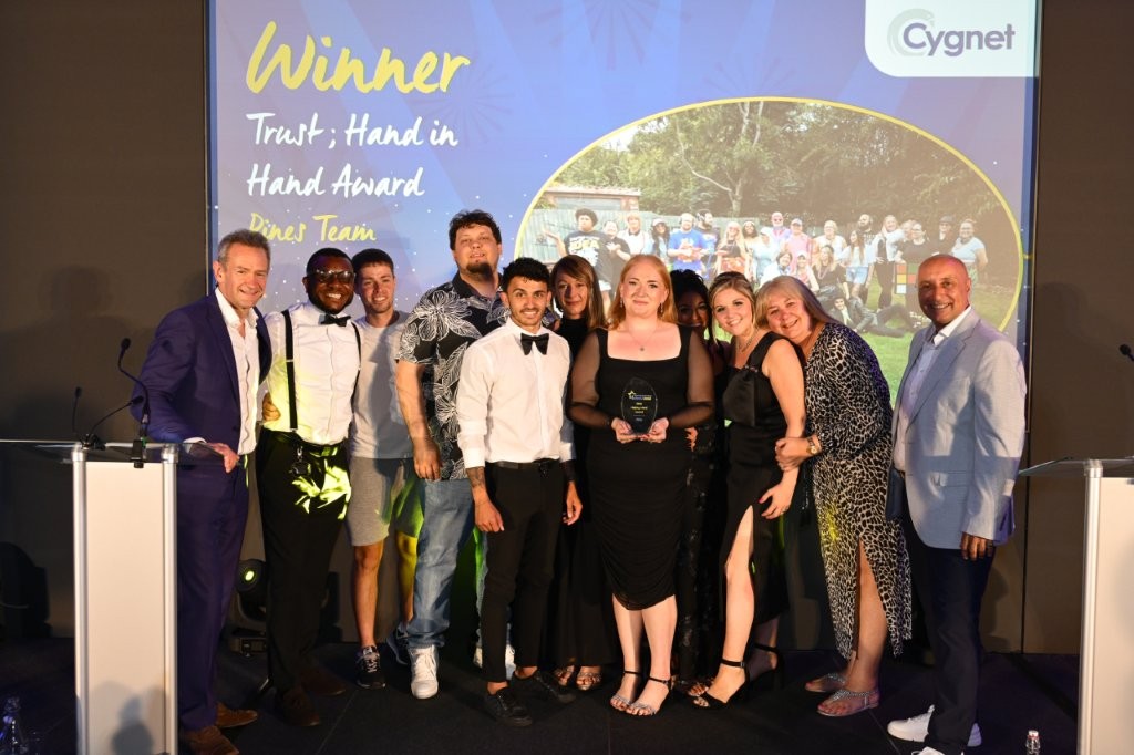 The winner of the Trust; Hand in Hand Award on stage with CEO Tony Romero and celebrity host Alexander Armstrong
