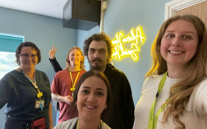 The team and a service user smiling in the newly opened social hub