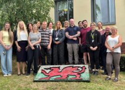 The team stood outside Cygnet Delfryn Lodge with a Welsh flag made of stones on the floor at their feet