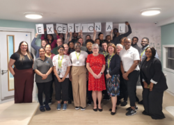 The team celebrating the rating at the hospital, holding the individual letters of exceptional in the air