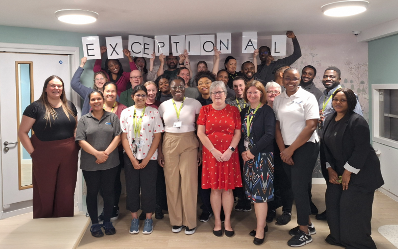 The team celebrating the rating at the hospital, holding the individual letters of exceptional in the air