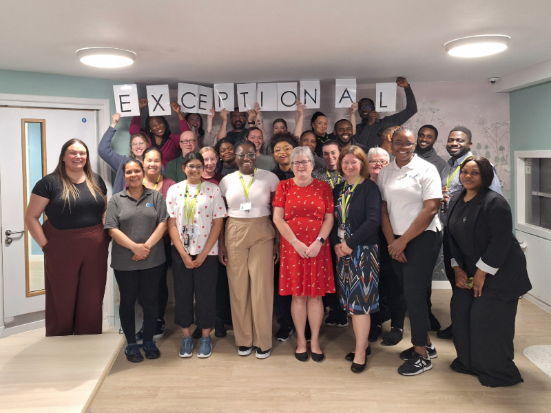 The team celebrating the rating at the hospital, holding the individual letters of exceptional in the air